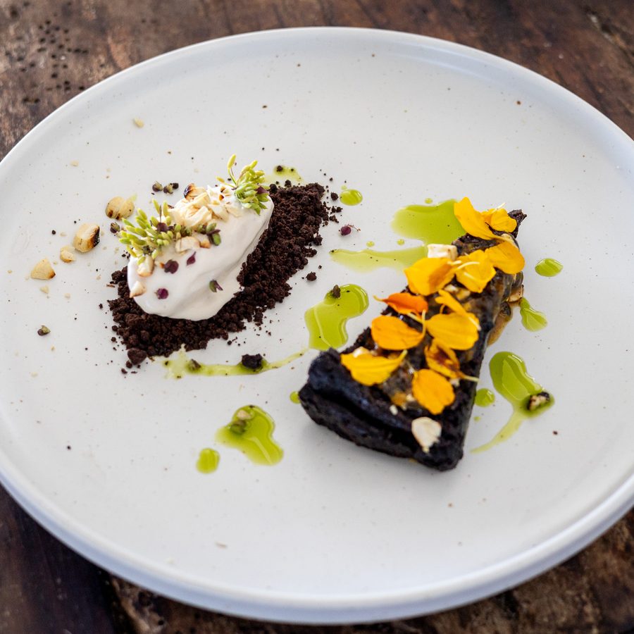 A chocolate dessert with orange flower petals on a white plate
