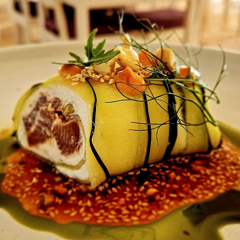A courgette-wrapped roll topped with nuts and herbs