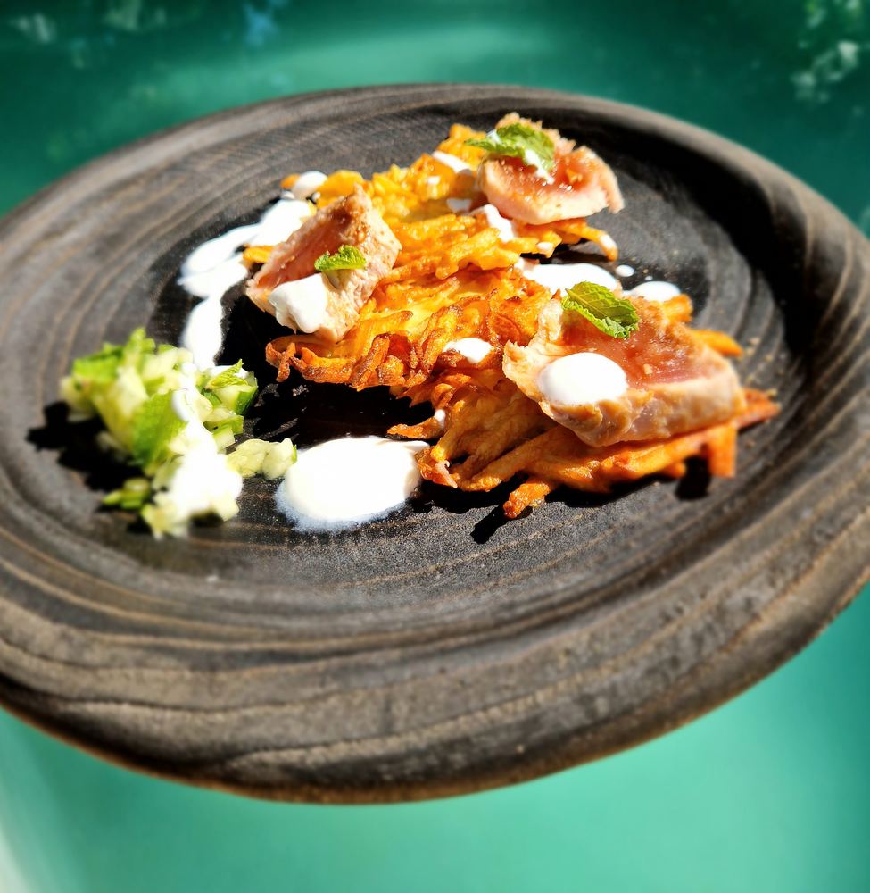 A plated dish on a dark wooden plate, held over the pool