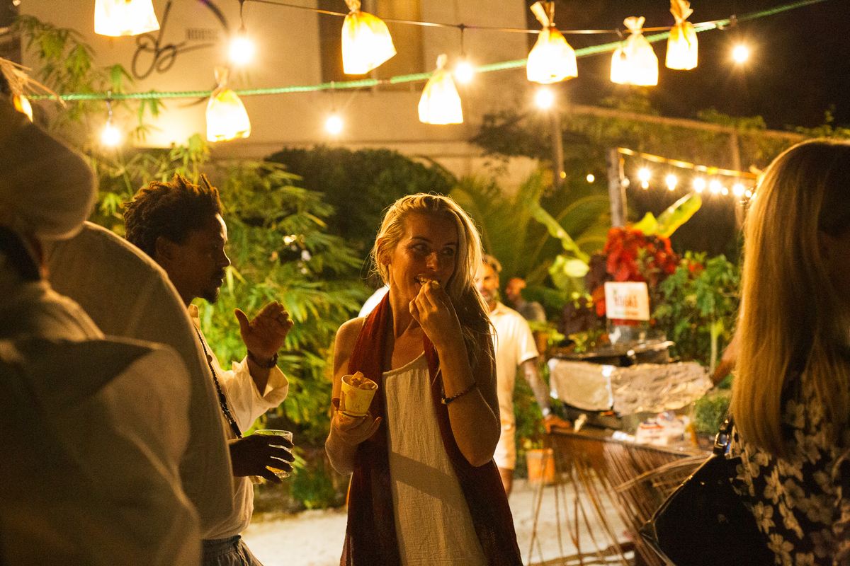 A guest tasting food between the market stalls under paper lanterns
