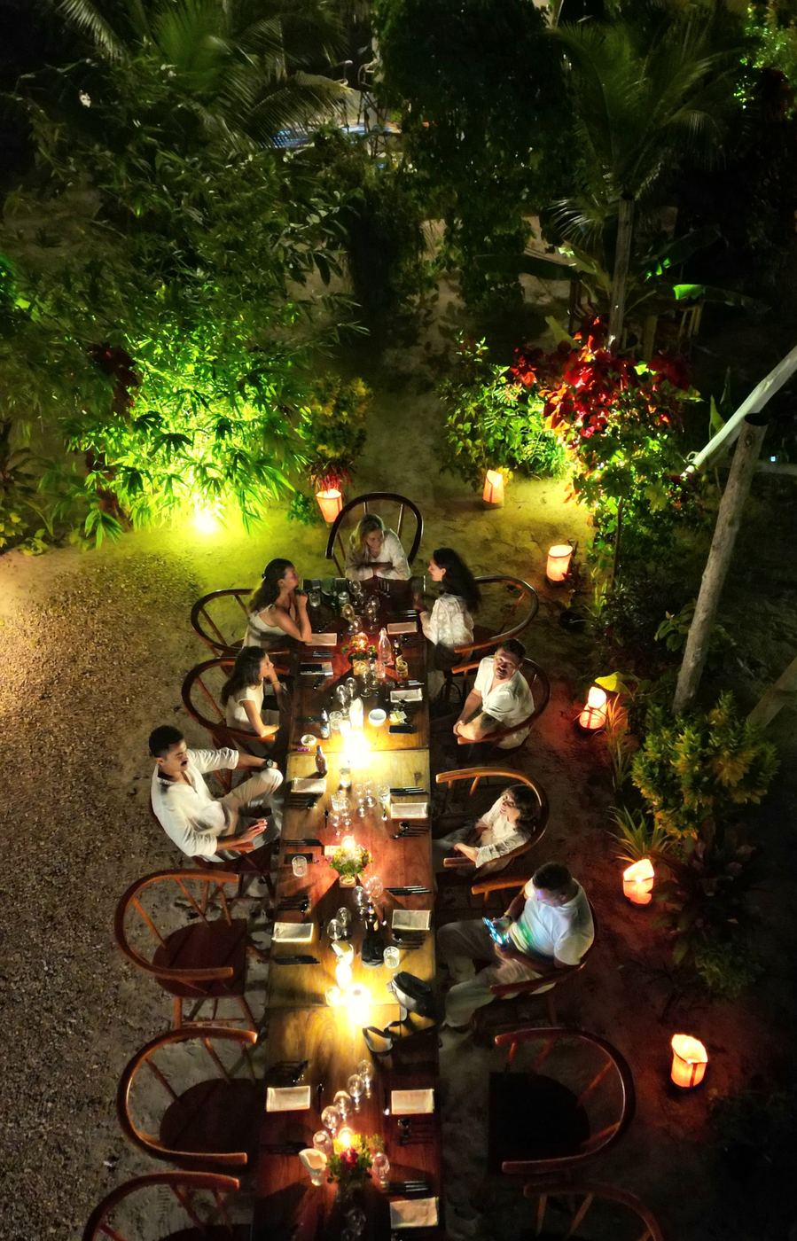A candlelit long-table dinner in the garden, seen from above