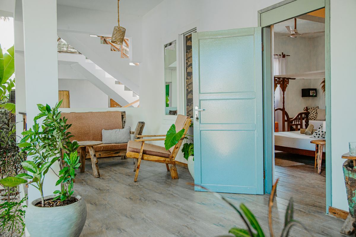 Lounge with wooden armchairs, plants and a pale blue door