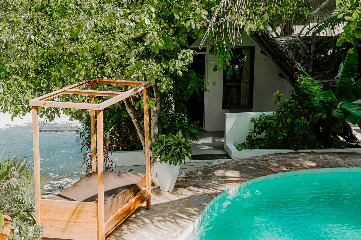 Swimming pool with a wooden daybed in the garden