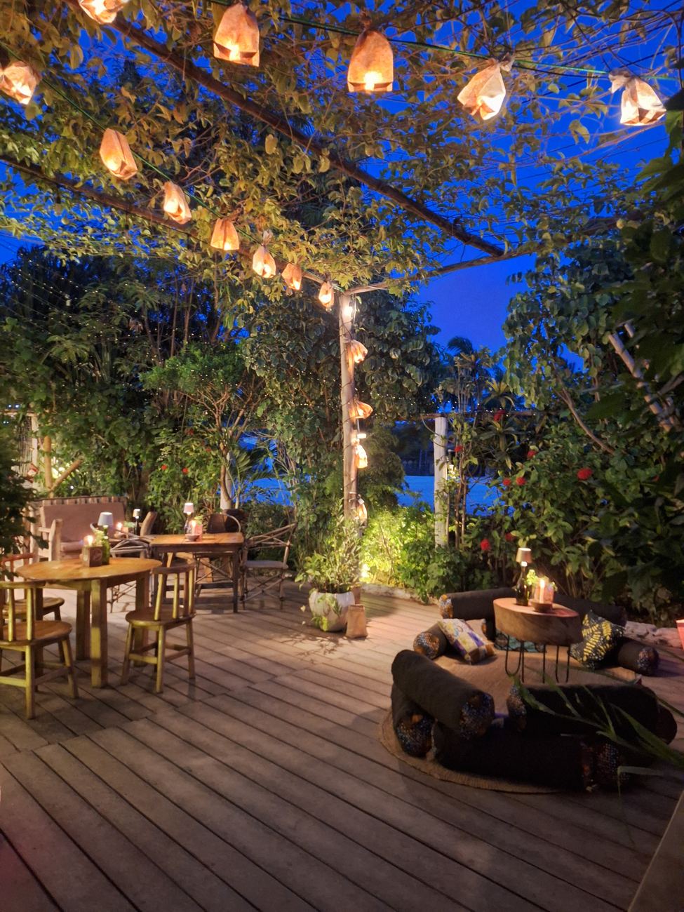 Wooden deck in the garden at dusk with lanterns hanging in the trees