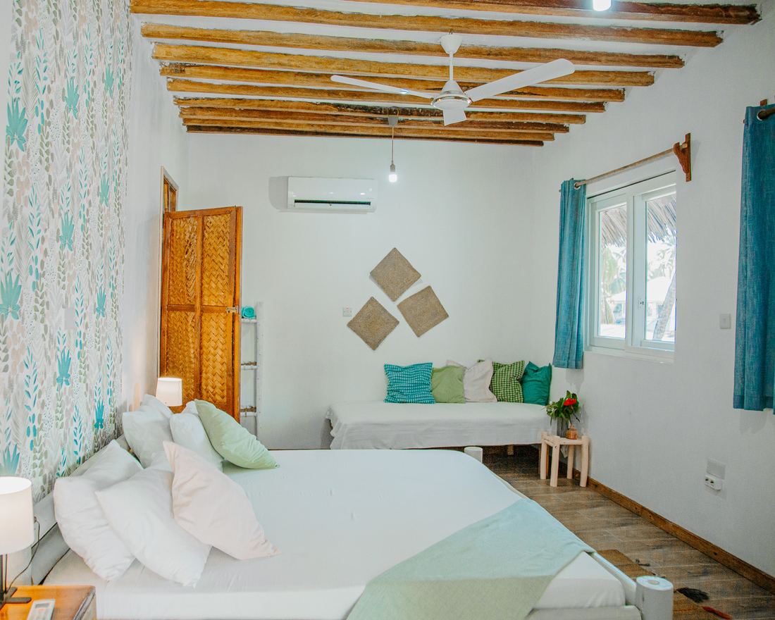 Room with blue curtains, a daybed and timber ceiling beams