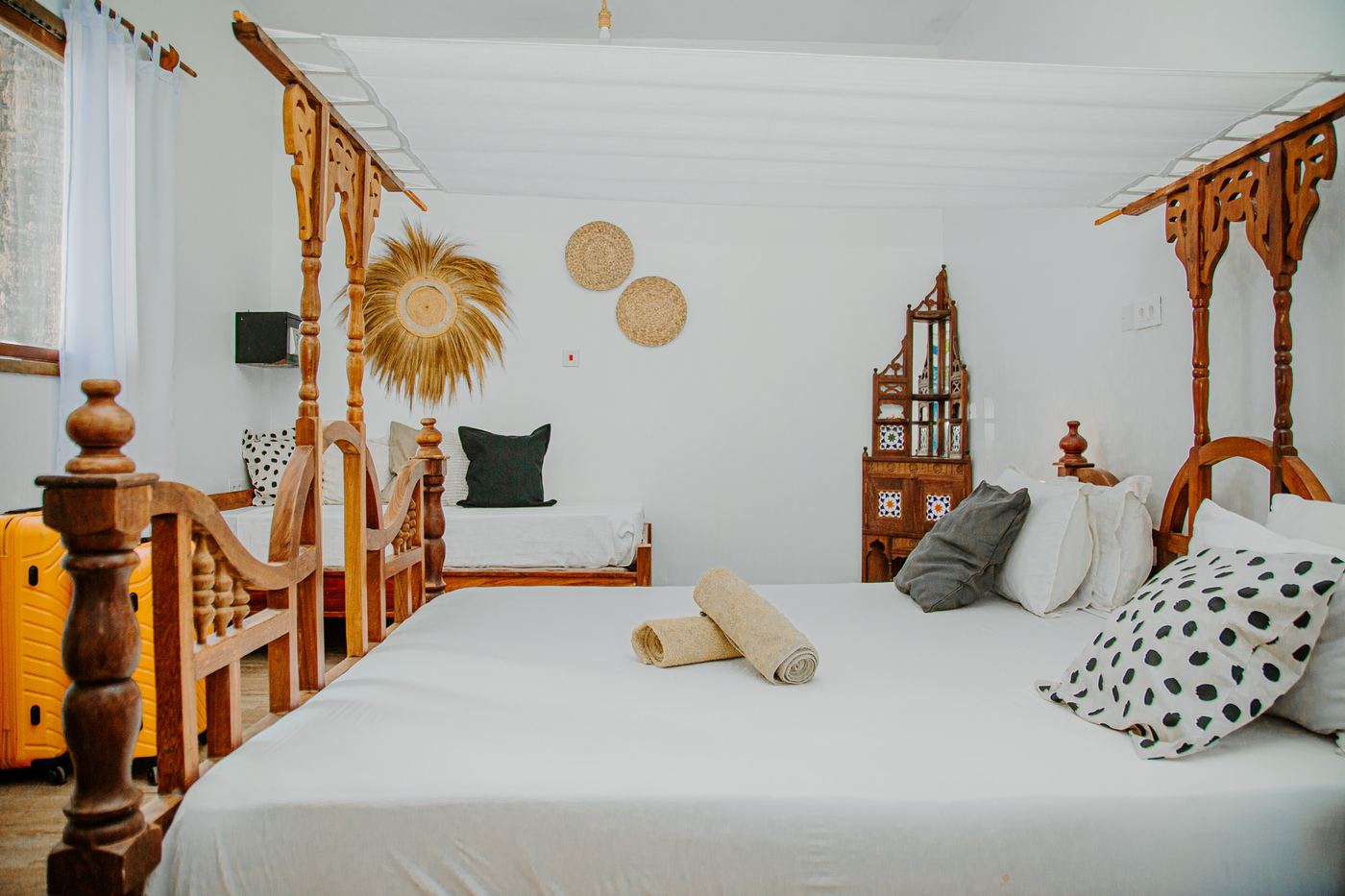 Room with a carved Zanzibari four-poster bed and white canopy