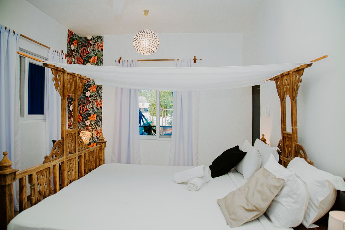 Room with a carved wooden bed and floral wallpaper