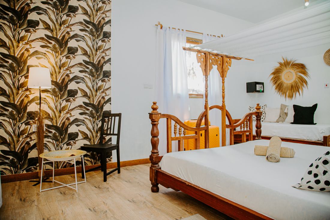 Room with palm-leaf wallpaper and a carved bed