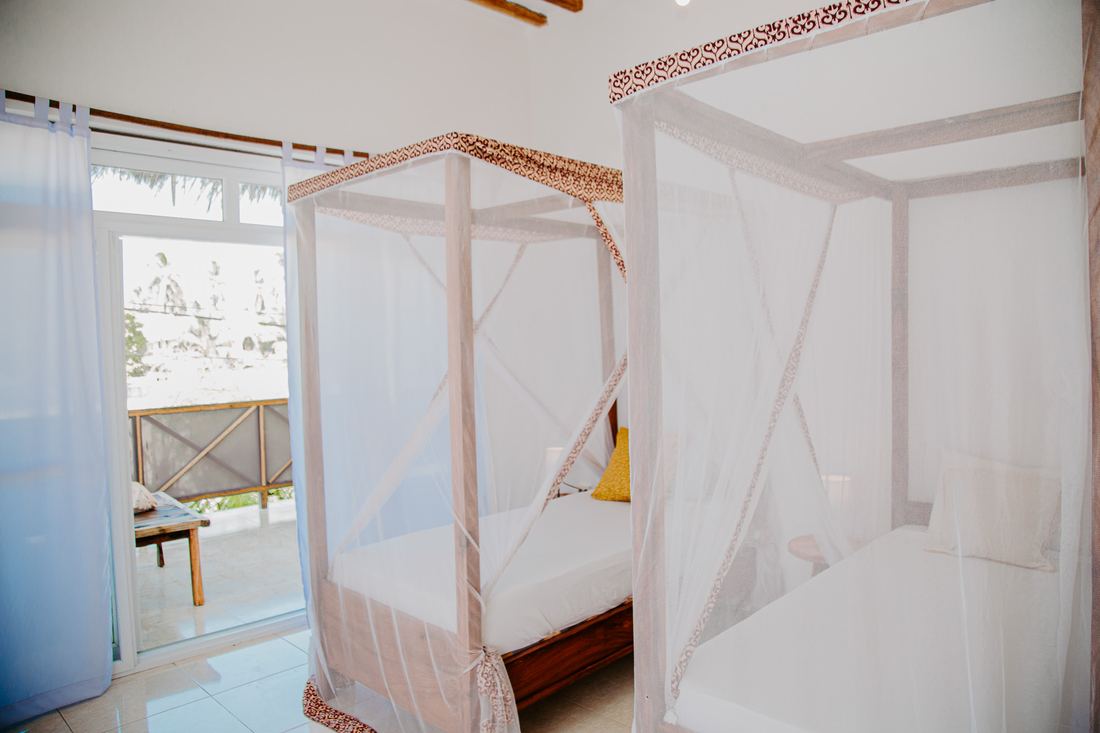 Twin room with two four-poster beds and mosquito nets