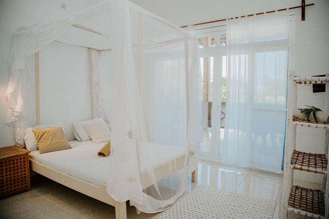 White room with a canopy bed and sliding glass doors